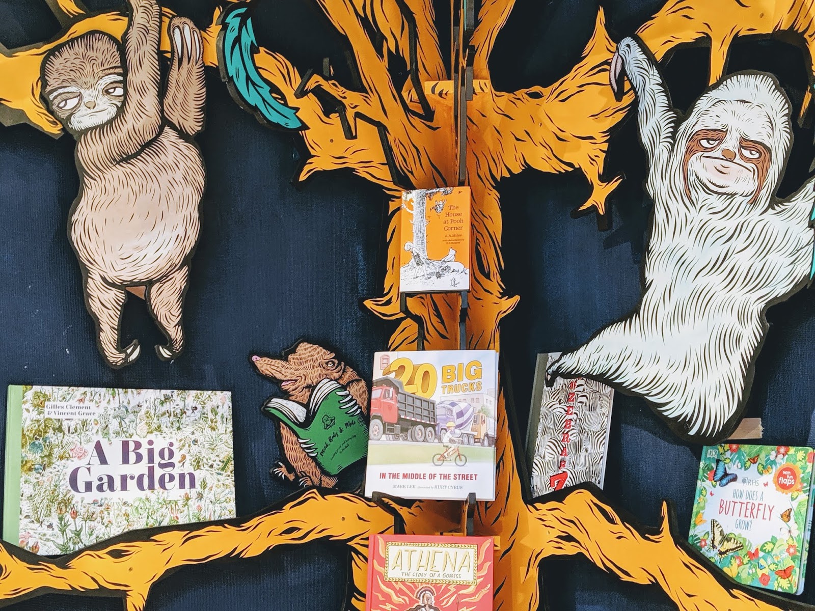 Cartoon sloths hanging in a tree with books in Mr B's children's section
