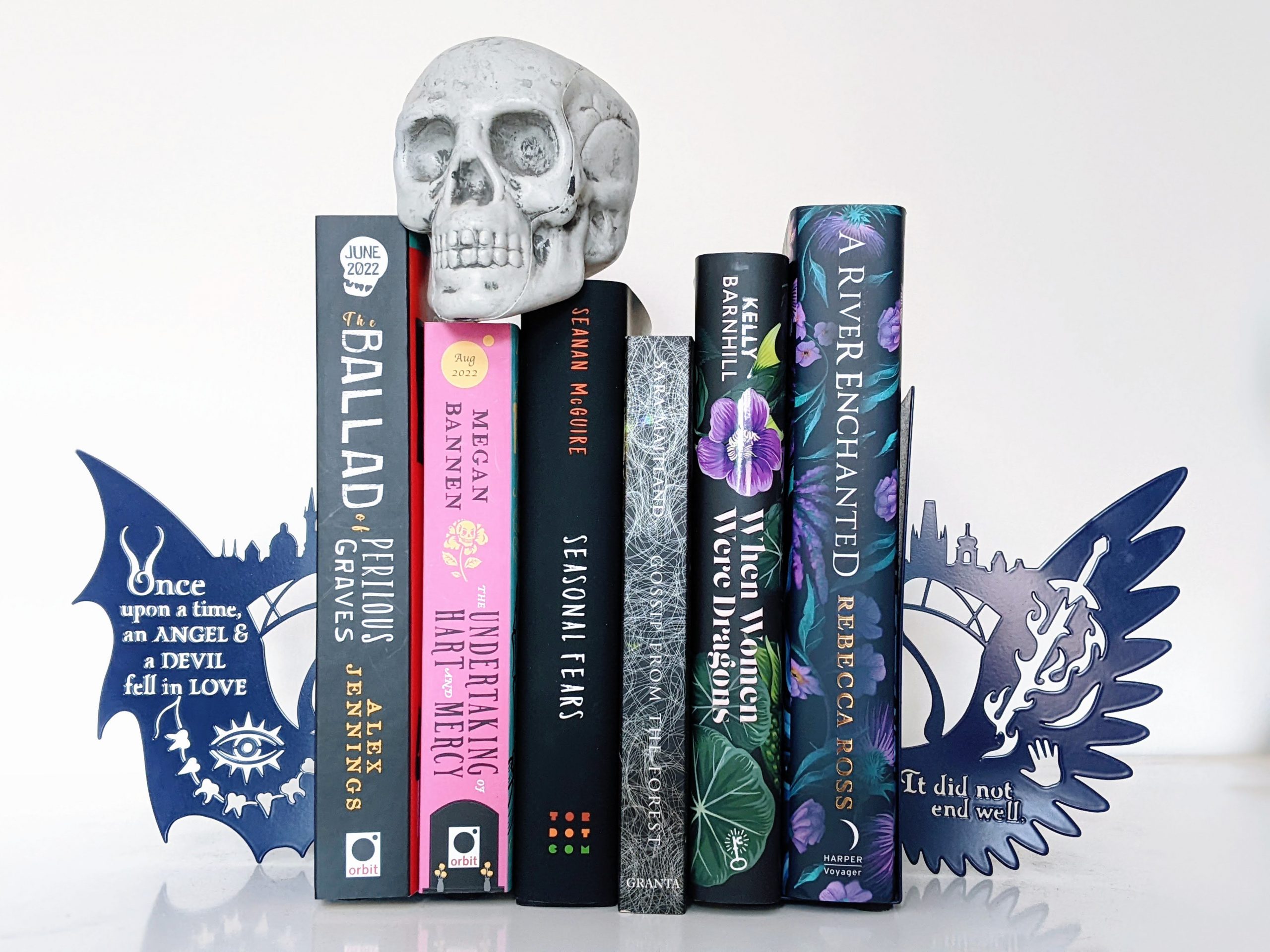 Six books (titles listed in post) in angel wing book ends with fake skull on top.