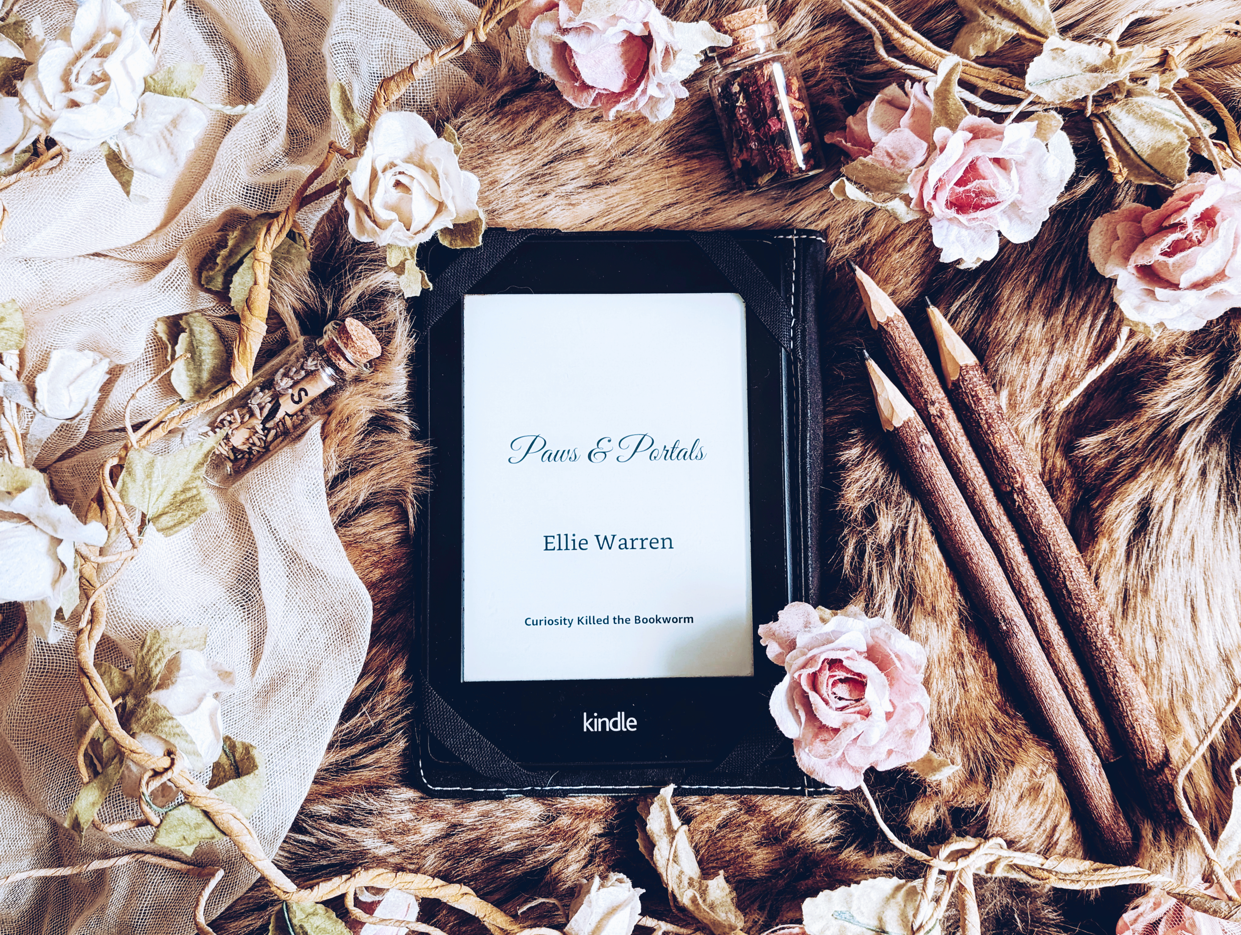 A Kindle showing the title page of Paws and Portals by Ellie Warren